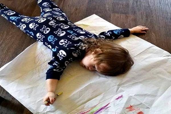 Kid asleep on his drawing.