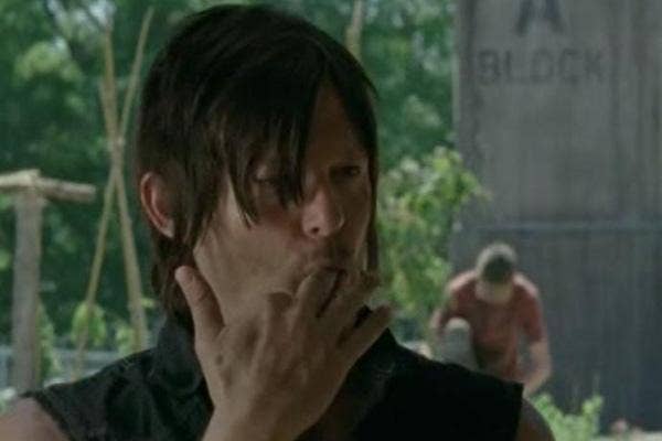 Norman Reedus as Daryl Dixon licking his fingers on The Walking Dead AMC