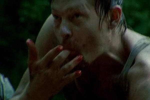 Norman Reedus as Daryl Dixon licking blood off his fingers on The Walking Dead AMC