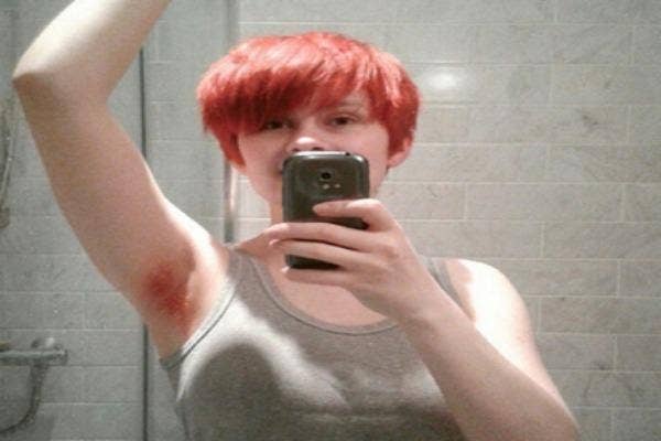 Woman with orange hair on her head and under her arms takes a selfie.