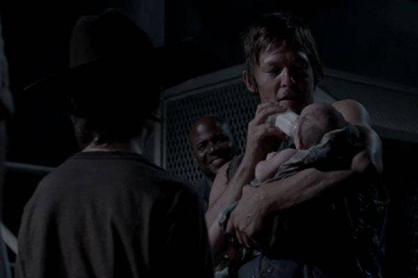 AMC The Walking Dead Melissa McBride as Carol Pelletier and Norman Reedus as Daryl Dixon holding baby Judith Lil Asskicker