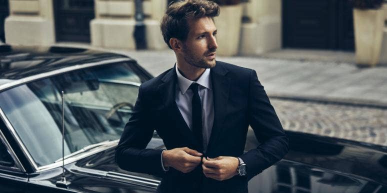 man in suit standing by car
