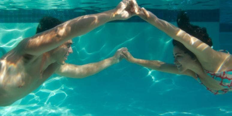 couple holding hands under water