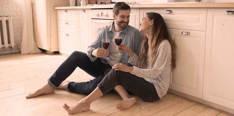 couple sitting on kitchen floor, drinking