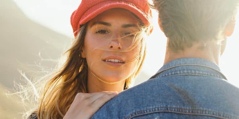 Woman in red hat looking over man's shoulder doing things after fight to keep together