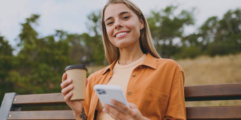 smiling happy woman on her phone drinking coffee