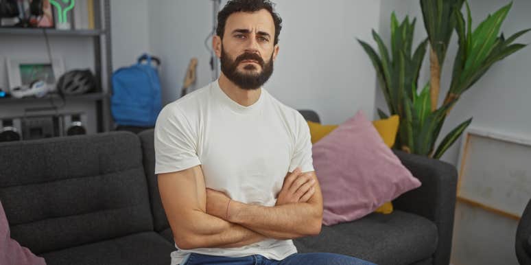 serious man sitting on couch with arms crossed
