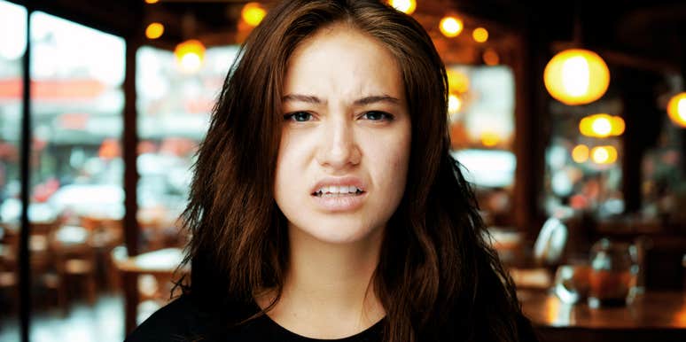 Woman at restaurant, repelled by surprising food habit. 