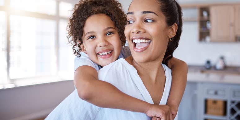mom giving daughter piggyback at home