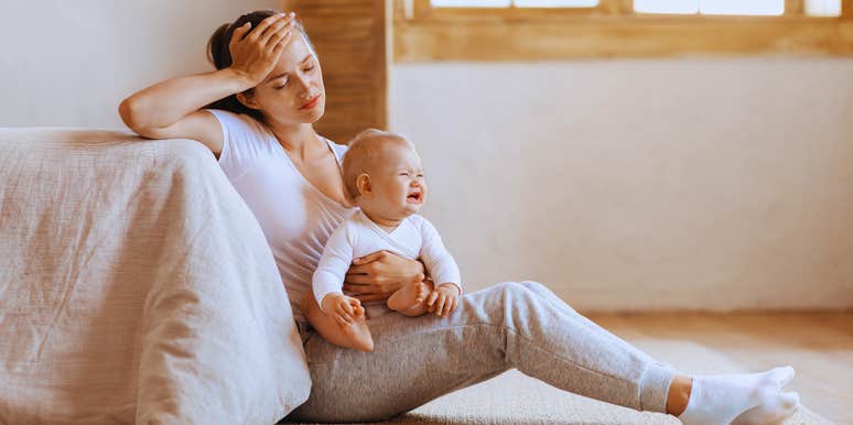 stressed out mom holding baby sitting on floor