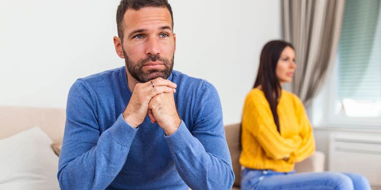 unhappy man sitting next to lazy wife on couch