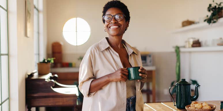 woman smiling while drinking coffee in kitchen