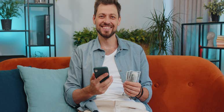 frugal man sitting on his couch holding money