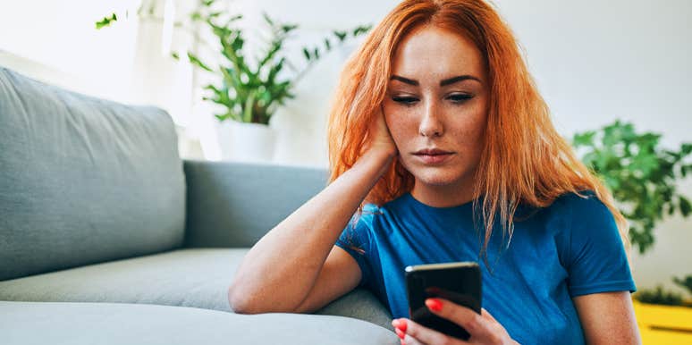 deeply unhappy woman looking at her phone