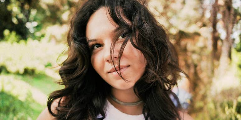 Woman with long hair in a park, pondering if she truly loves him or is just emotionally attached