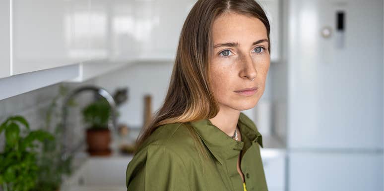 woman standing in her kitchen thinking about her struggling finances