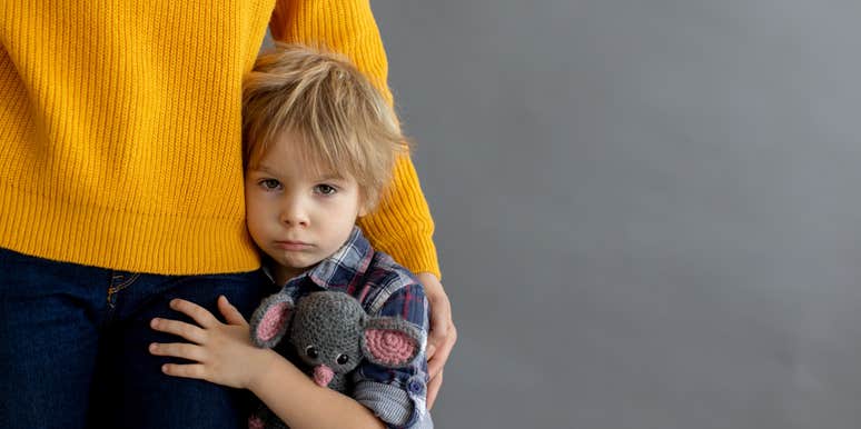 sad toddler hugging mom's leg