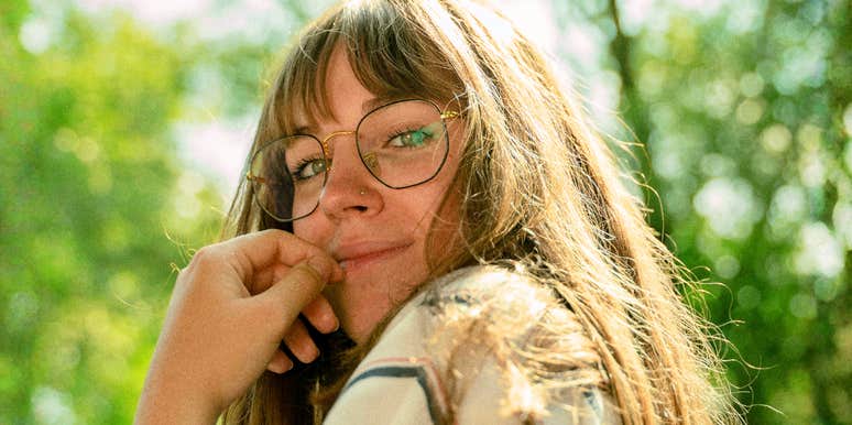 Woman looking over her shoulder with a subtle flirty smile, capturing the scientific signs of real human chemistry and falling in love.