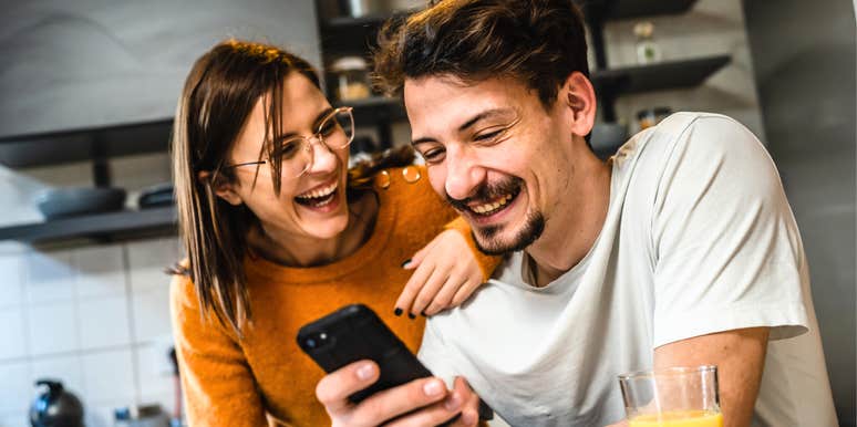 Happy couple laughing together in kitchen, showing the positive outcomes of relationship repair and how couples counseling can restore connection and joy.