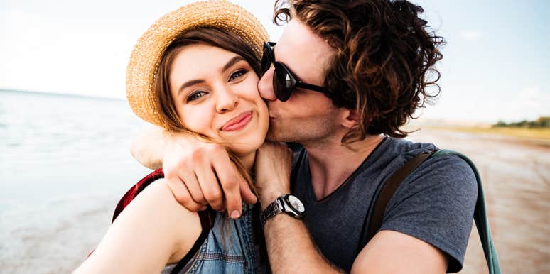Playful couple on the beach taking a selfie showing the art of fun and habits of couples who aren’t boring and blah