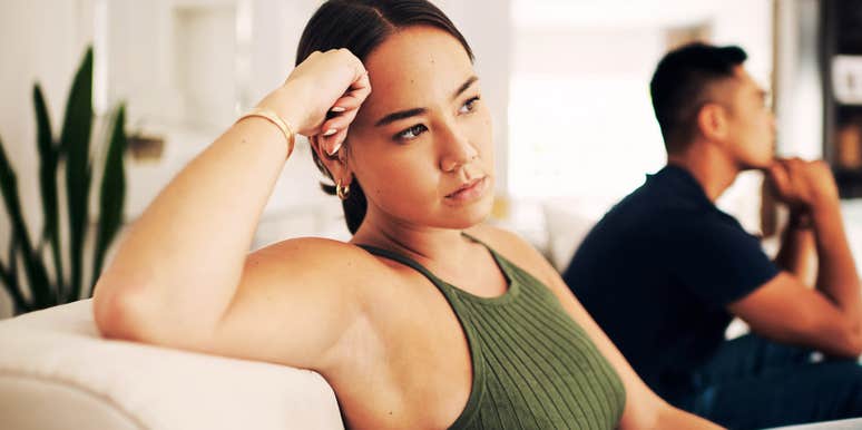 Couple sitting silently on couch, emotional distance and tension showing clear signs it’s time for couples counseling and relationship repair.