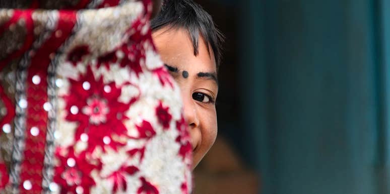Young Pakistani girl holding her mother’s waist, reflecting the deep bond and pain of being a daughter of a sold mother.