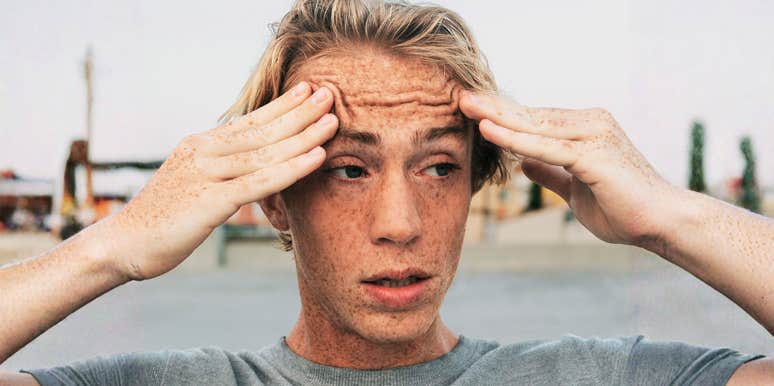 Anxious man holding his temples with wide eyes, when anxiety causes racing heart and stress.