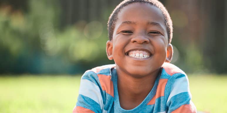 little boy smiling while lying on grass outside