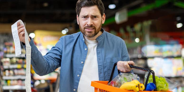 frustrated man holding receipt after grocery shopping