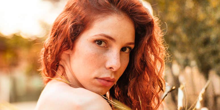 Close-up of red-haired woman looking back intensely, reflecting the emotional grip of obsessive love that studies say can secretly sabotage success and happiness.