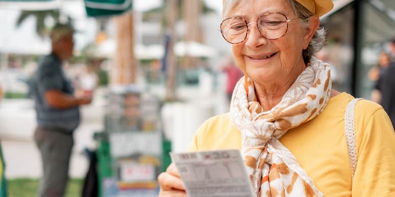 smiling old woman writing on lottery ticket