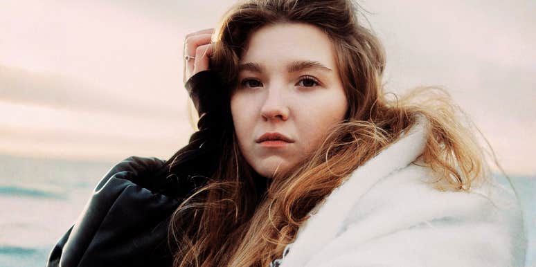 Woman resting her hand on her head in a moment of self-compassion, embodying the simple habits of people who don't bully themselves for being human.