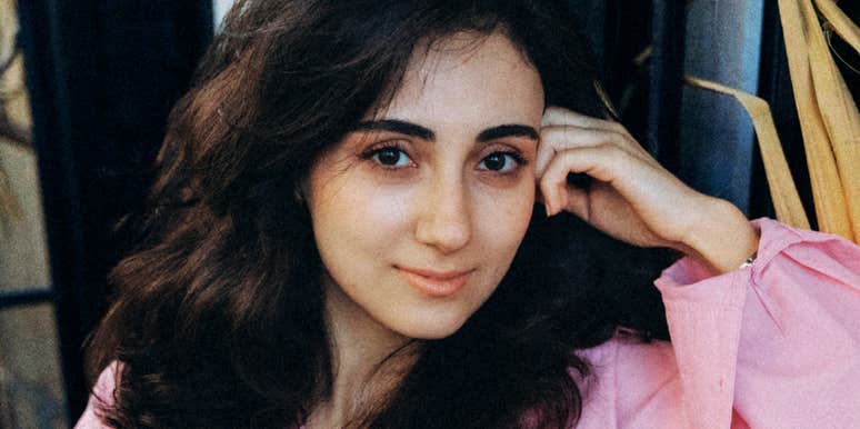 Fulfilled woman sitting on the ground outdoors in a quiet moment.