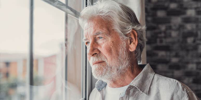 serious boomer man looking out window