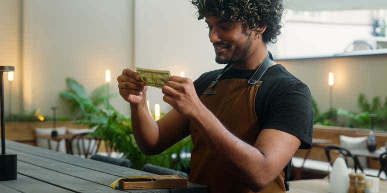 happy waiter receiving tip from customer