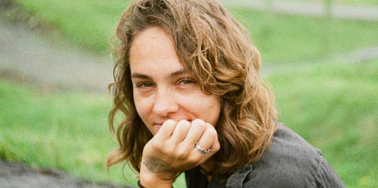 Fulfilled woman sitting on the ground outdoors in a quiet moment.