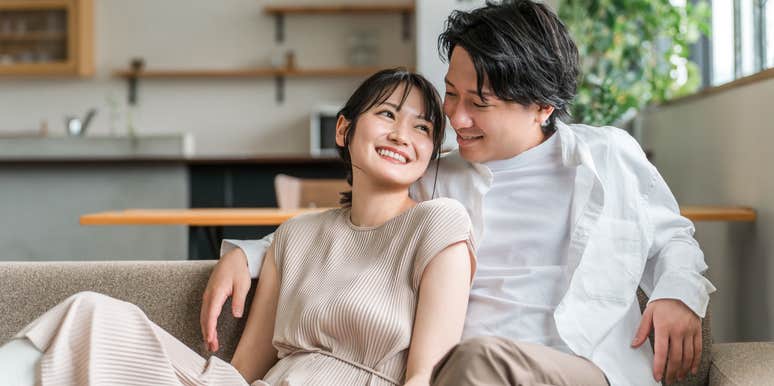 happy couple cuddling on couch at home
