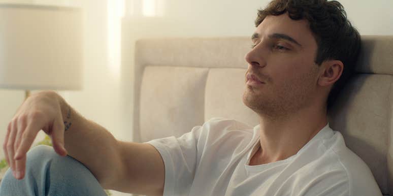 unhappy man sitting up in bed thinking