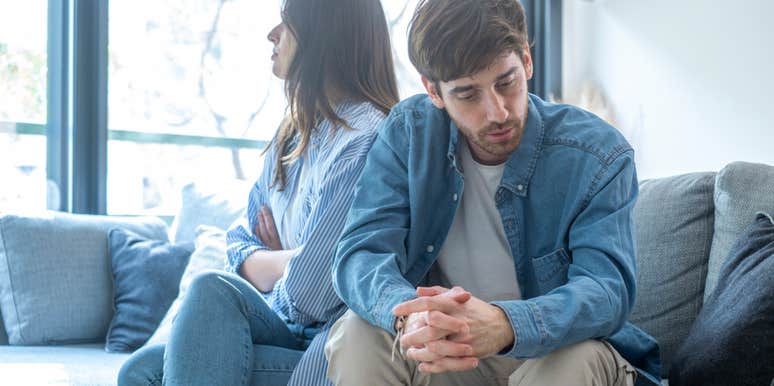 couple sitting in stiff tense silence on a sofa, illustrating the hidden issue experts say people ignore when they insist their marriage is ‘fine’ right before divorce