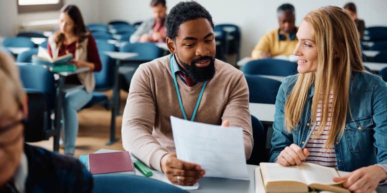 professor showing student graded assignment in class