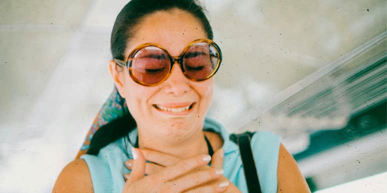 Woman wearing sunglasses giving a polite smile that suggests discomfort or awkwardness.