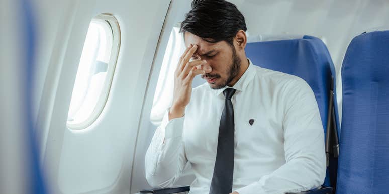 stressed man sitting on plane near window