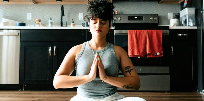 Woman sitting in quiet meditation with hands pressed together, capturing the ancient practice of spiritual alignment that brings body and mind back into balance.