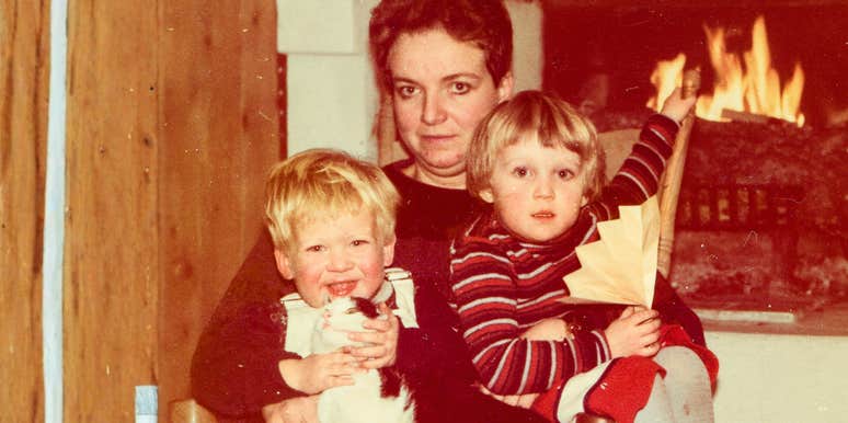 Vintage family photo of a mom and two young children by a fireplace showing the unhinged things someone thought were normal growing up