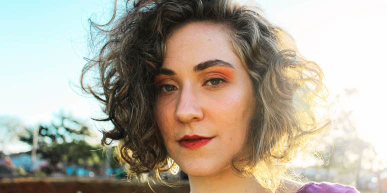 Woman with a calm expression standing outdoors in soft sunlight