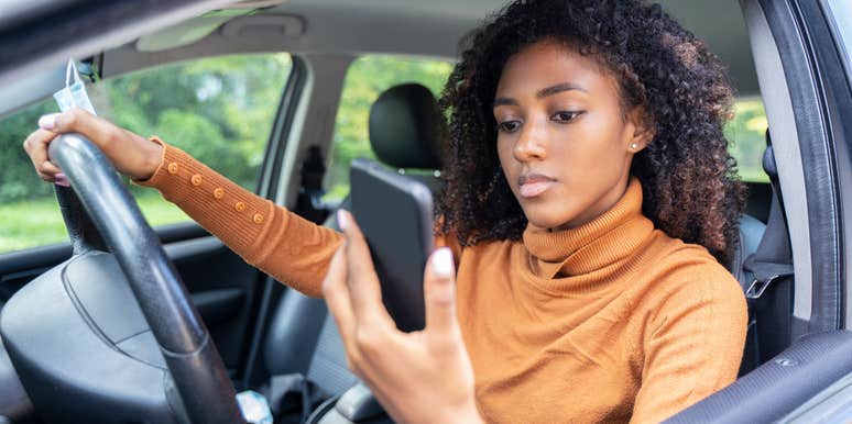 woman looking at phone while driving for delivery service