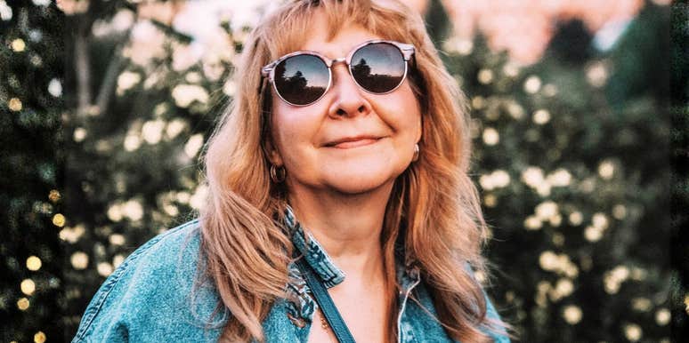 Woman wearing sunglasses outdoors, appearing calm, confident, and content.