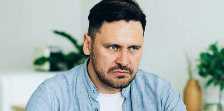 Serious-looking man sitting indoors with a tense expression