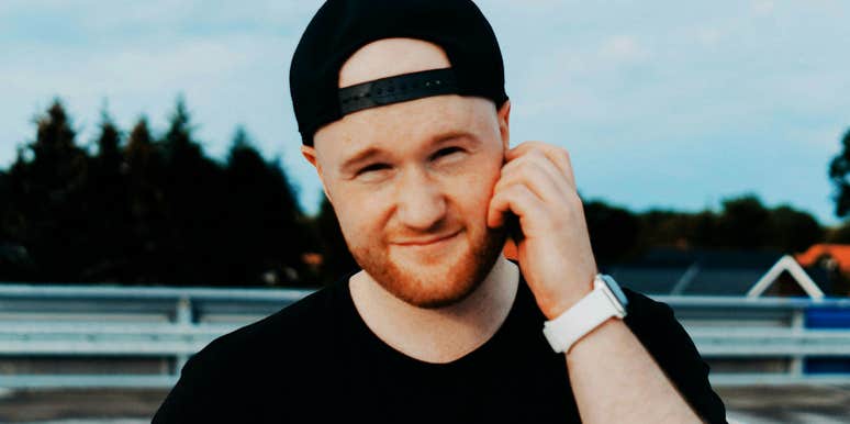 Man hand near face with a backwards hat. 