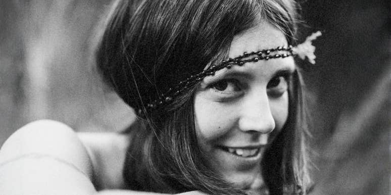 A black-and-white portrait of a young girl wearing a delicate headband, smiling softly.